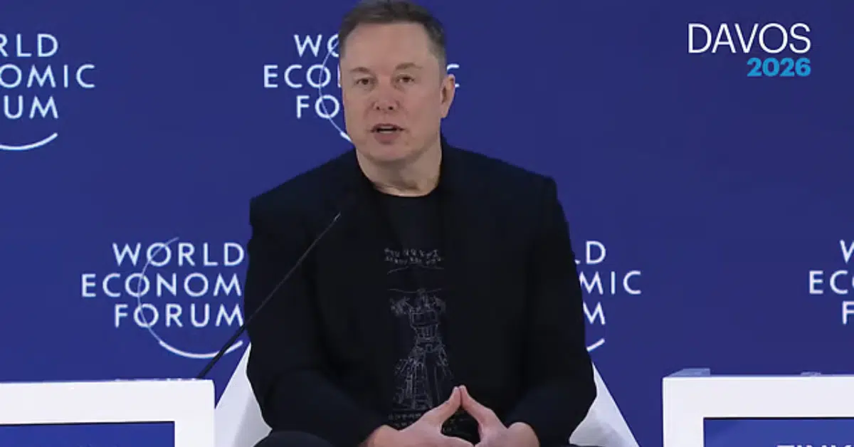 A technology executive speaking on stage at the World Economic Forum, seated against a blue backdrop labeled “World Economic Forum” and “Davos 2026,” addressing an audience during a panel discussion.