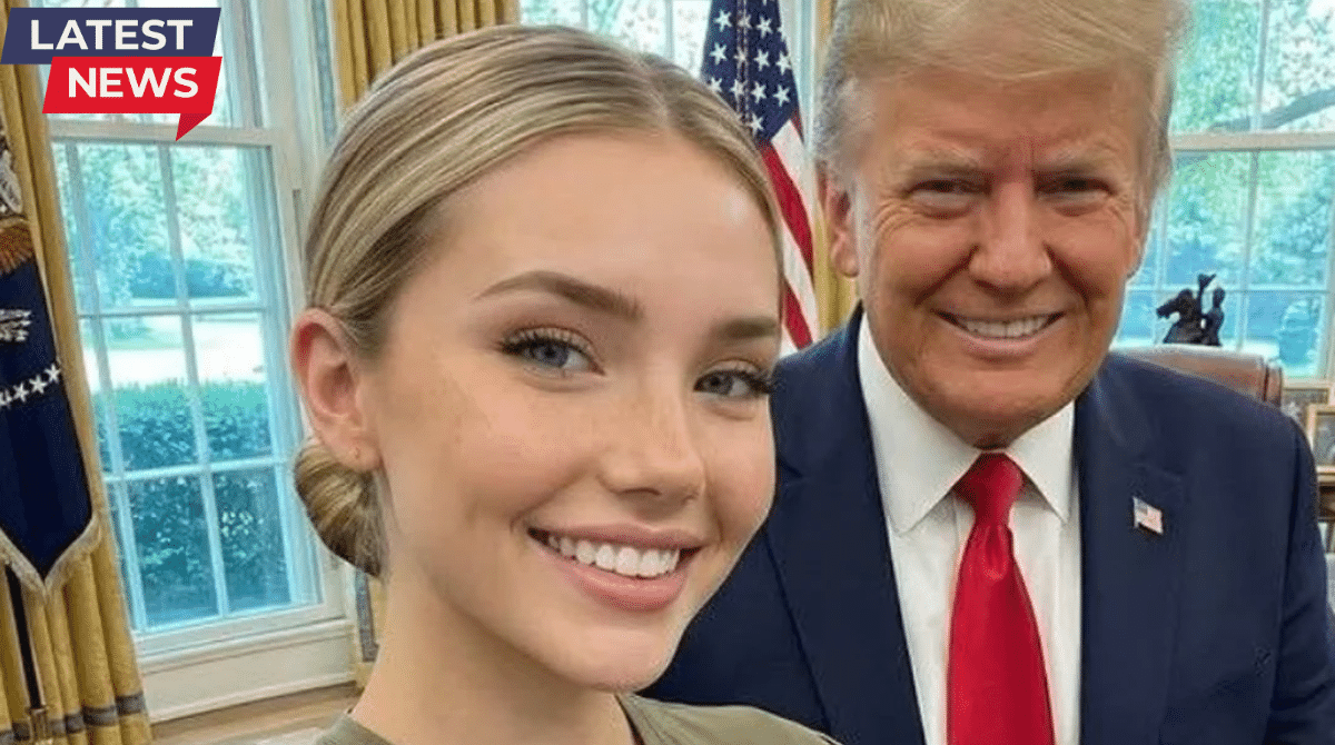 A young blonde woman taking a selfie with a suited public figure in an office setting, with an American flag visible in the background.